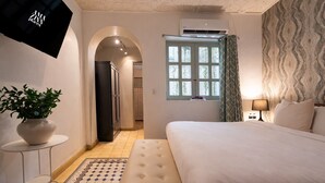 Ein Schlafzimmer mit einem Bett, einem Blumentopf, einem Nachttisch, einer Lampe und einem Fenster mit Vorhängen.