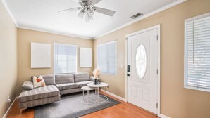 A living room with a gray sectional sofa, a small round table, and a white door with a decorative glass panel.