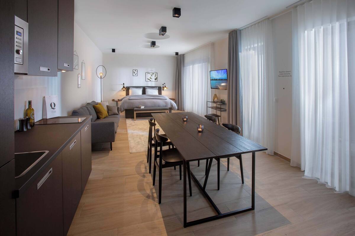 Ein modernes Hotelzimmer mit Küche, Essbereich, Bett und Fernseher.