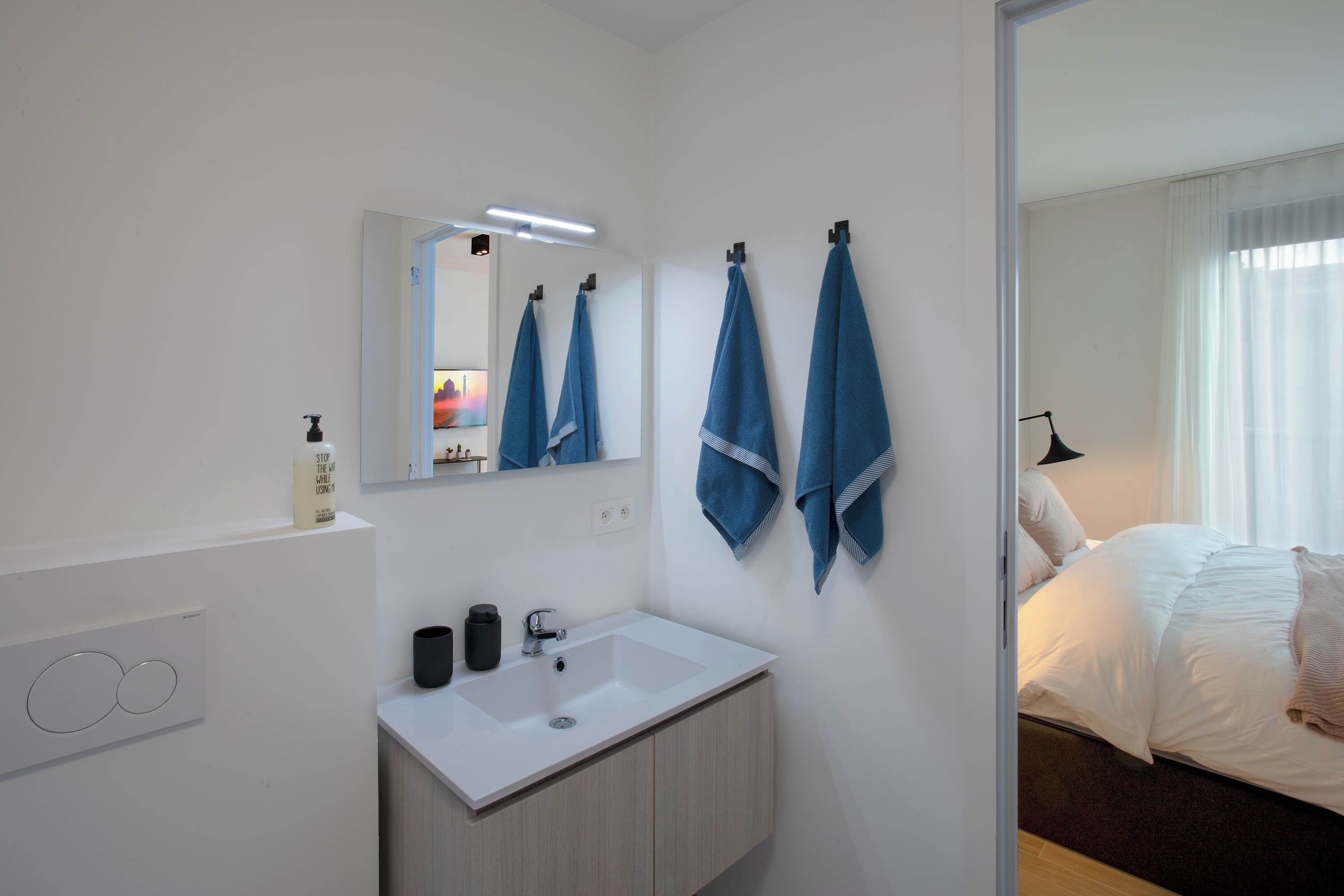 Une salle de bain moderne avec un lavabo blanc, un miroir et un porte-serviettes.