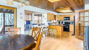 Un intérieur en bois comprenant un coin repas, une cuisine et une grande fenêtre.