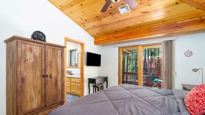 Une chambre avec un grand lit, une armoire en bois et une porte-fenêtre coulissante donnant sur un balcon.