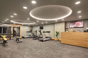 Une salle de sport équipée de tapis de course, de vélos elliptiques et de poids libres.