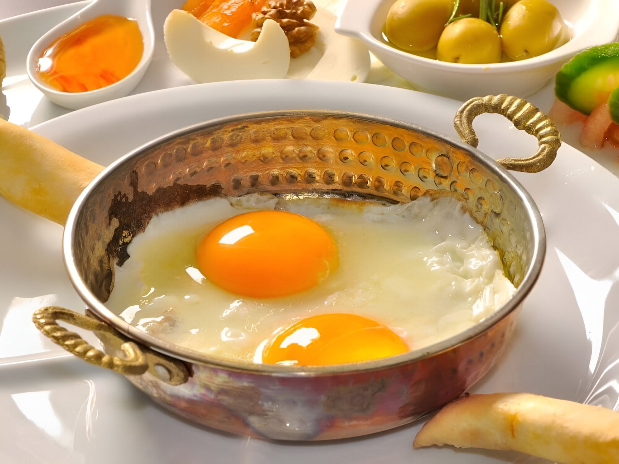 Une table mise pour le petit-déjeuner, avec des œufs dans un bol décoratif, entourée de divers aliments.