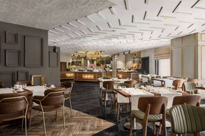 Un restaurant au décor moderne, doté d’un bar central, de plusieurs tables et d’une variété de types de sièges.