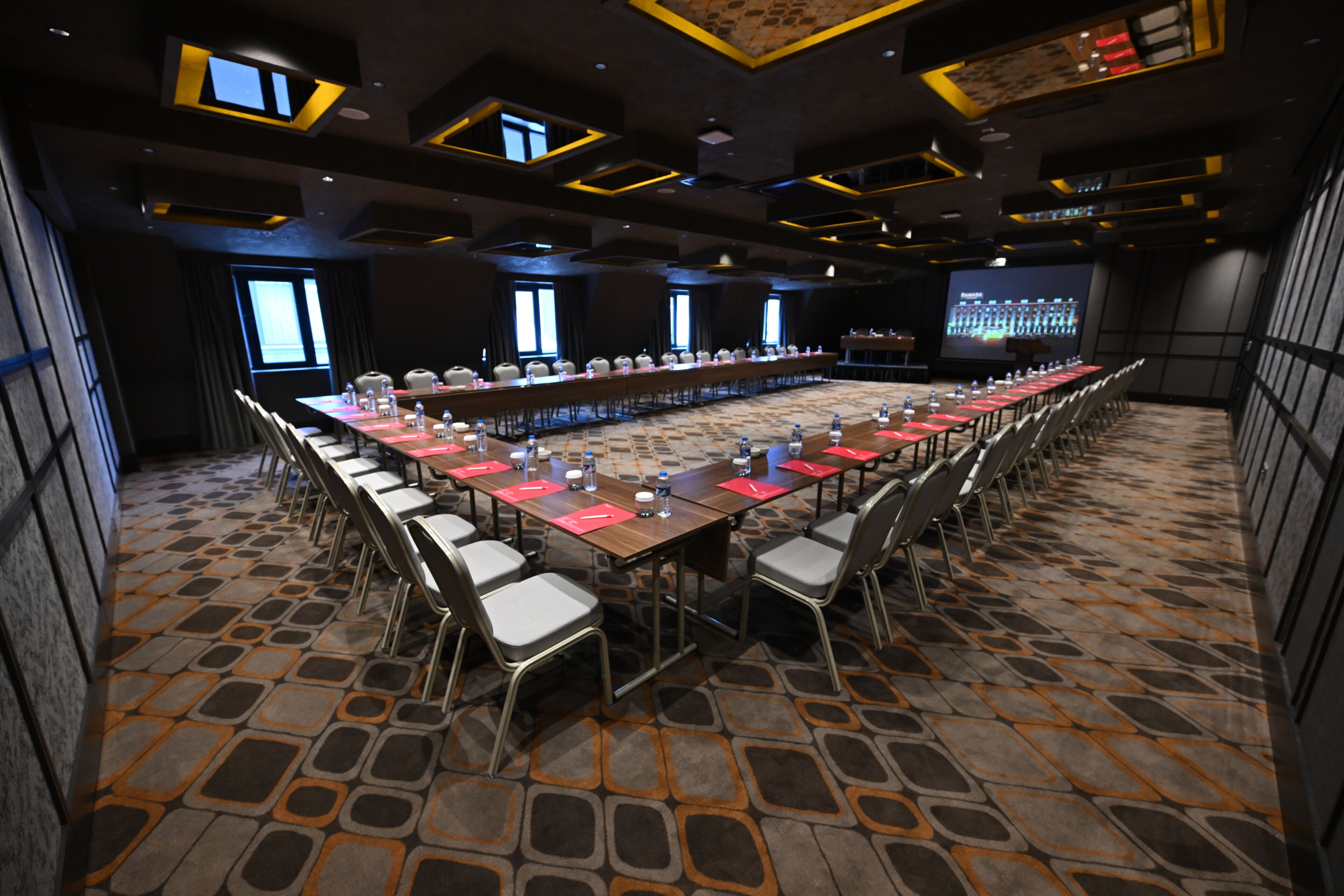 A conference room with a long table, chairs, and a projector screen.