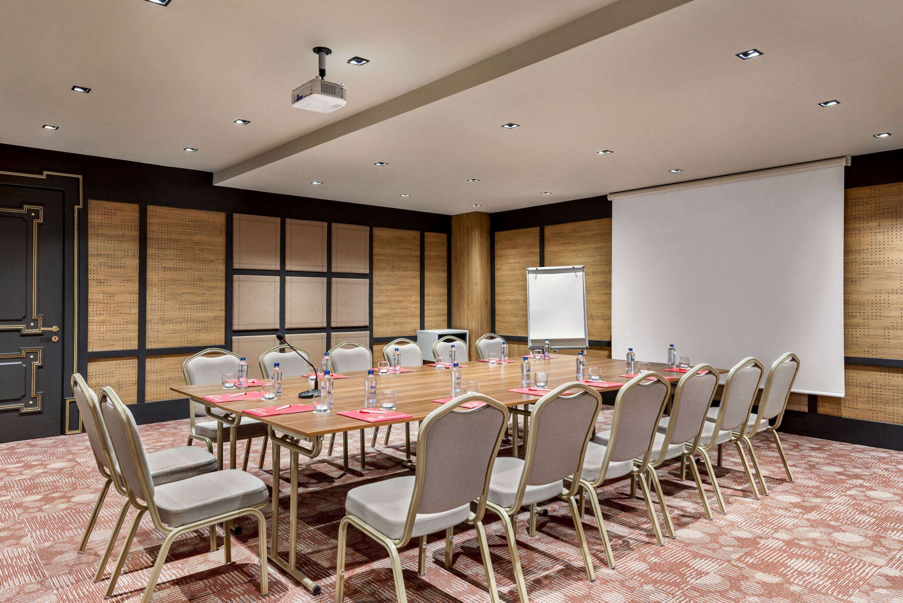 A conference room with a long table, chairs, a projector, and a whiteboard.