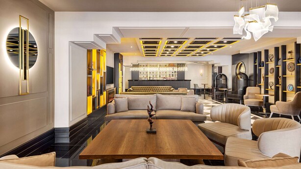 Ein modernes Interieur mit einer zentralen Sitzecke, einer Bar und einer gut beleuchteten Decke mit außergewöhnlichen Leuchten.