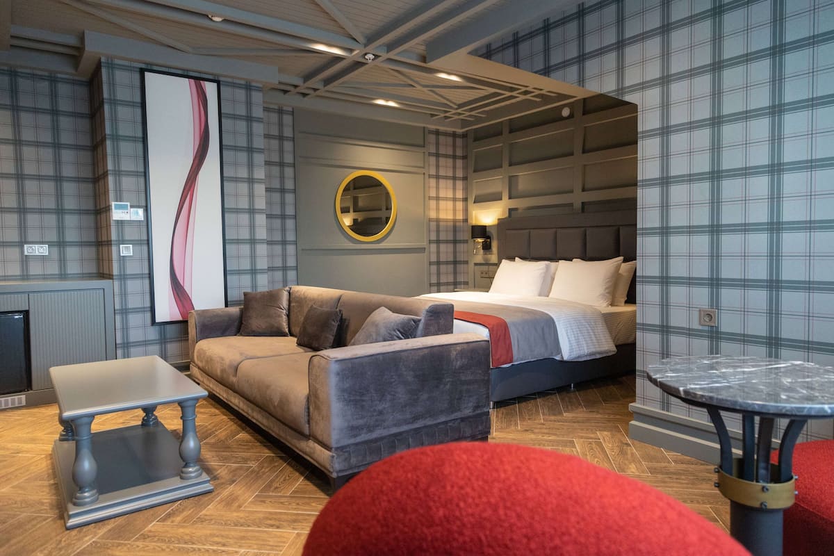 Une chambre d’hôtel moderne avec un canapé, un lit, un miroir rond et une petite table.