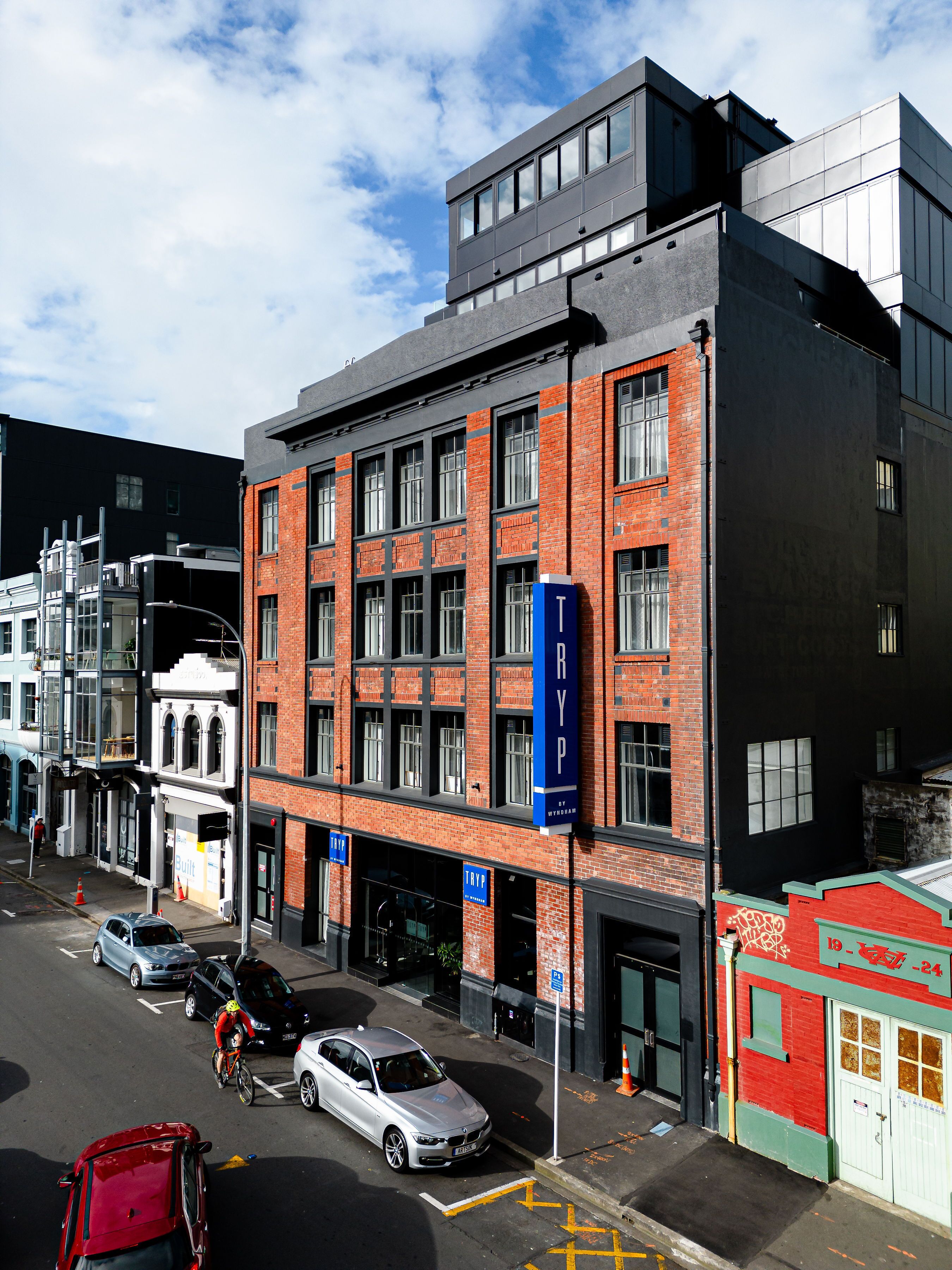 A multi-story building with a mix of brick and modern architecture, featuring large windows and a prominent blue sign.