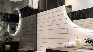 Une salle de bain moderne avec une douche à parois de verre, des toilettes blanches, un meuble-lavabo en bois et un grand miroir.