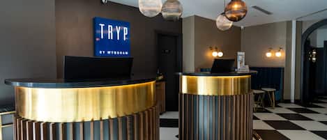 A reception area with two counter desks, a blue sign above the left desk, and pendant lighting.