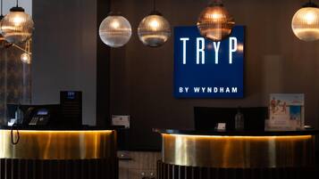 Una recepción con un letrero azul que dice "TRYP BY WYNDHAM" y una cámara de seguridad en la parte superior.