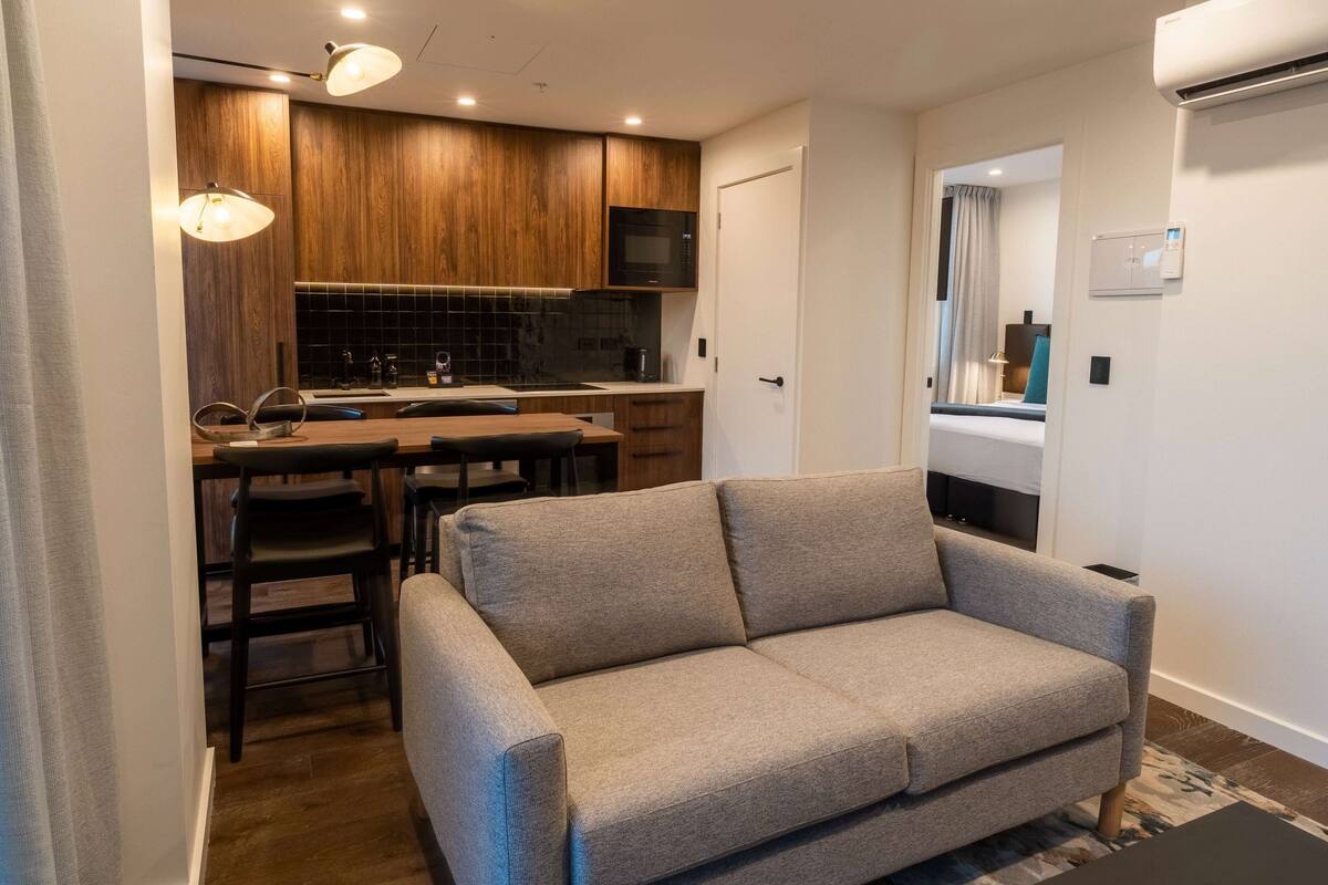 A modern kitchen with wooden cabinets, a central island, and pendant lighting.