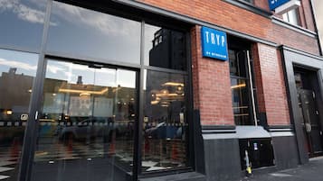 Un bâtiment doté de grandes fenêtres en verre et d’une enseigne bleue sur laquelle on peut lire « TRYP BY WYNDHAM ».