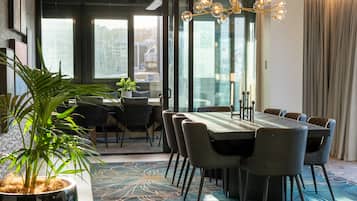 A modern dining area with a large table, chairs, and a potted plant.