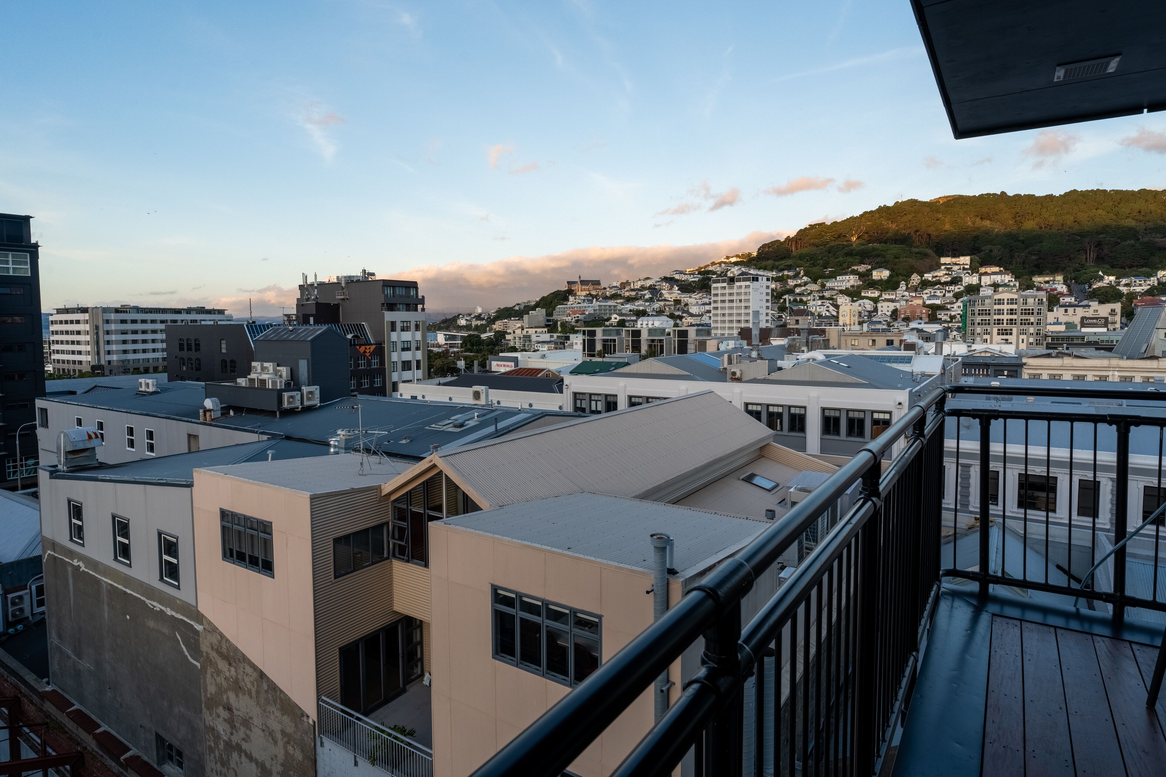 Un paisaje urbano con edificios modernos, vista de una colina con vegetación y cielo despejado.
