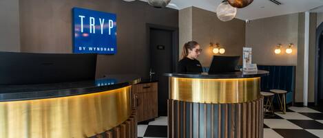 A reception desk with a 'TRY' sign, a laptop, and a check-in counter.