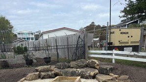 Un espacio al aire libre con grava, una jardinera de madera, un borde de madera y rocas.