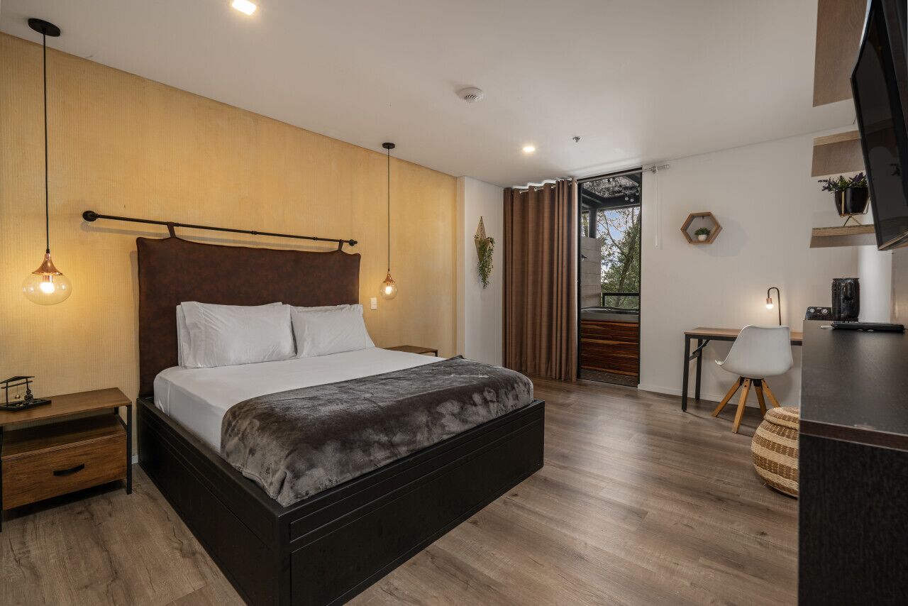 Un dormitorio moderno con una cama grande, suelo de madera y vistas al exterior.