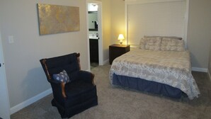 A bedroom with a bed, a chair, a ceiling fan, a window with blinds, and a painting on the wall. - Cheerful 2-Bedroom Townhouse with Pool (Clarksville)