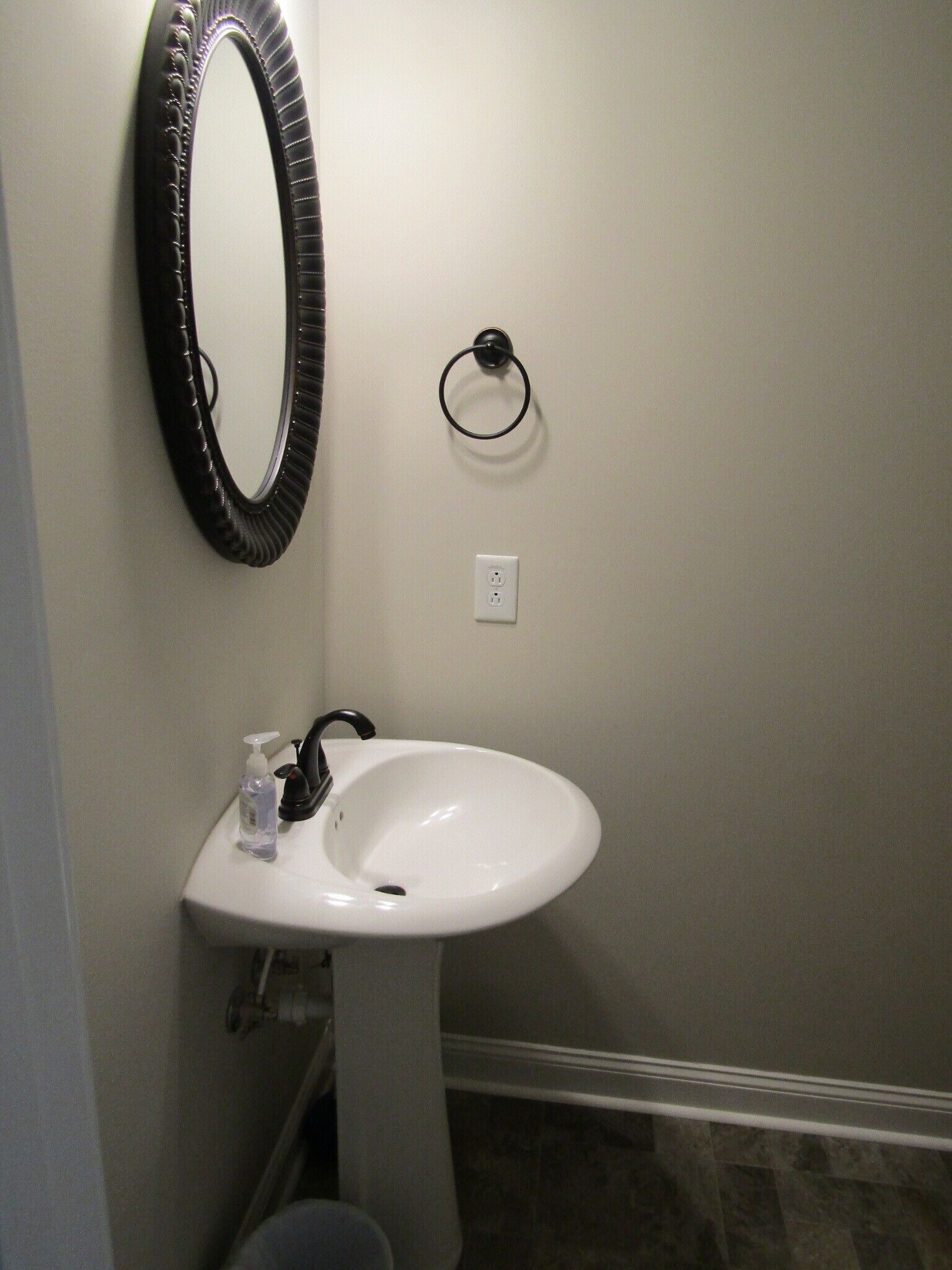 Une salle de bain avec un lavabo blanc, un miroir noir et des toilettes.