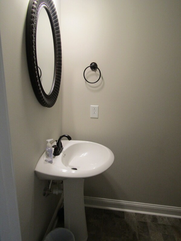 Un baño con un lavamanos blanco, un espejo negro y un inodoro.