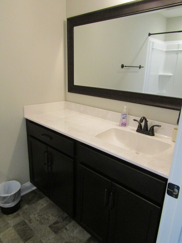 A bathroom with a white sink, black cabinets, and a large mirror.