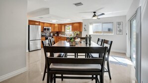 Eine moderne Küche mit Holzausstattung, ein Essbereich mit großem Tisch und Stühlen sowie ein Deckenventilator.