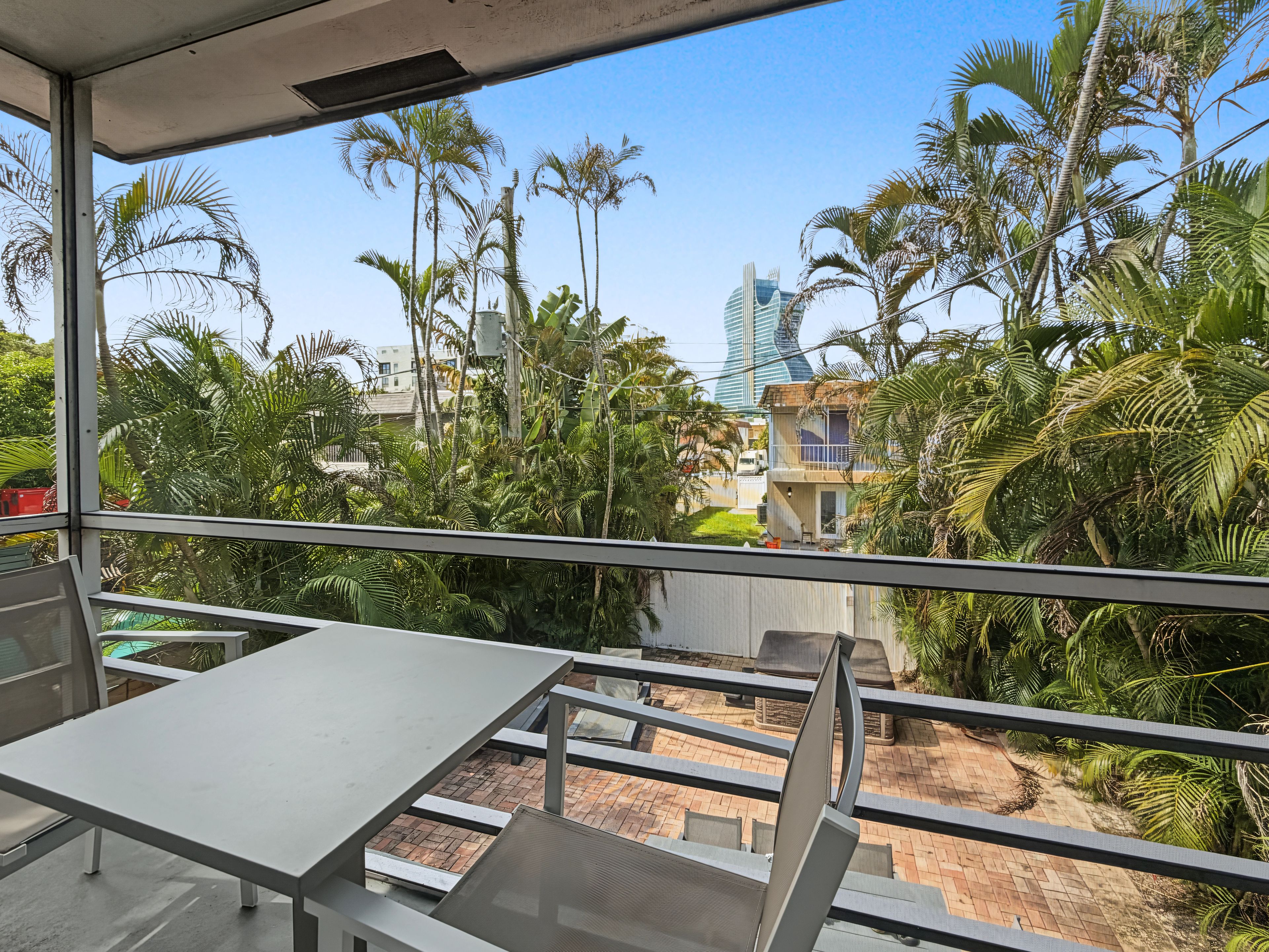 A balcony with a view of palm trees and a modern building.