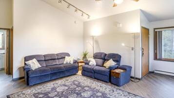 Ein Wohnzimmer mit einem dunkelblauen Sofagarnitur, einem gemusterten Teppich, einem Deckenventilator und einer Stehlampe.