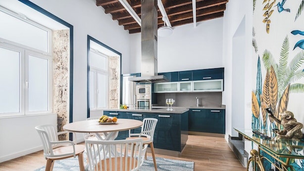 A modern kitchen with a central island, white chairs, and a dining table.