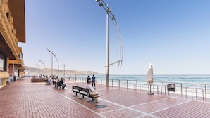 A seaside promenade with benches and street lamps, overlooking the ocean.