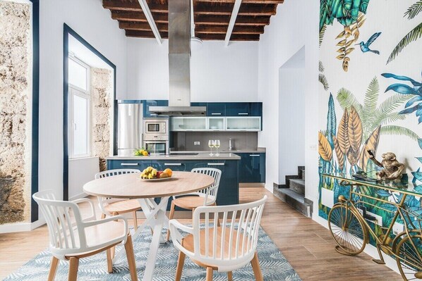 Una cocina moderna con una isla central, electrodomésticos integrados y un comedor con sillas blancas.