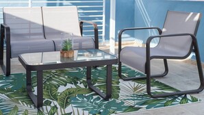 A patio area with a glass-top table, two chairs, and a small potted plant.