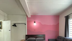 Ein Schlafzimmer mit einem Bett, einer Couch, einem kleinen Tisch und einer Wandleuchte.