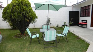 A patio with a table and four chairs, a large umbrella, and a small tree. - Hotel D lina Princess suites (San Cristóbal de las Casas)
