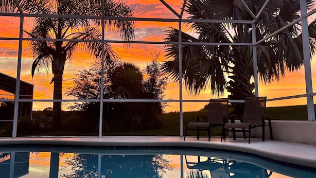 A pool with a sunset view, surrounded by palm trees and a clear sky. - Stunning Renovated Villa Overlooking Golf Course (Davenport)