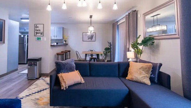 Un salon moderne avec un canapé bleu foncé, une table à manger et une cuisine en arrière-plan.
