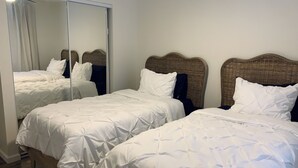 A hotel room with two single beds, each with white bedding and a woven headboard.