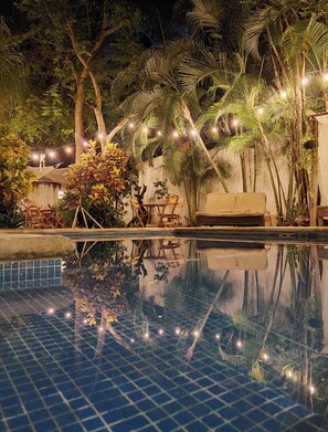 A pool area with a tiled floor, a sofa, and string lights.