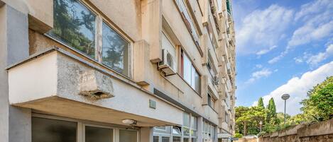 A multi-story building with a stone facade, large windows, and a narrow pedestrian pathway.