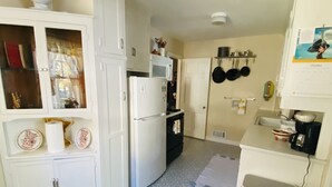 Una cocina compacta con armarios blancos, un refrigerador, un microondas y un lavamanos.