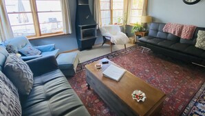 Una sala de estar con un sofá, una mesa de centro, una chimenea y un reloj en la pared.