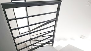 Una escalera con barandilla de metal y paredes blancas.