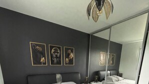 Un dormitorio moderno con una cama grande, una mesita de noche, un espejo y decoración en la pared.