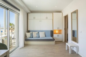 A modern room with a built-in sofa, white cabinets, a small table, and a large window offering a view of the beach. - Beach Front Studio w/Premium View -Astro Quarteira (Loulé)