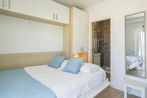 A bedroom with a bed, a walk-in shower, and a large mirror.