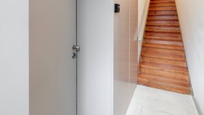 Un pasillo estrecho con una escalera de madera que sube a un piso superior.