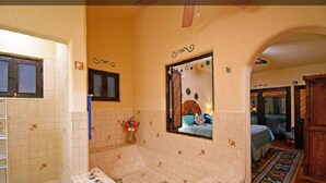 A bathroom with a bathtub, a mirror, and a window.